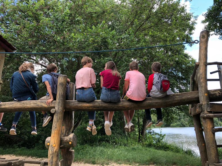 Eindruck - Jugendfreizeit in Lüsche (Jugendliche sitzen auf einem Holzstamm und sind von hinten fotografiert)